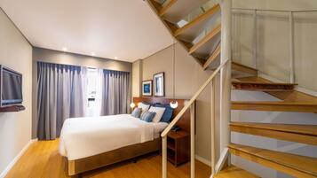 Una habitación de hotel con cama, televisor, escritorio y escalera.