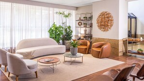 Una sala de estar moderna con un sofá, sillones, una mesita de centro y un elemento decorativo en la pared.
