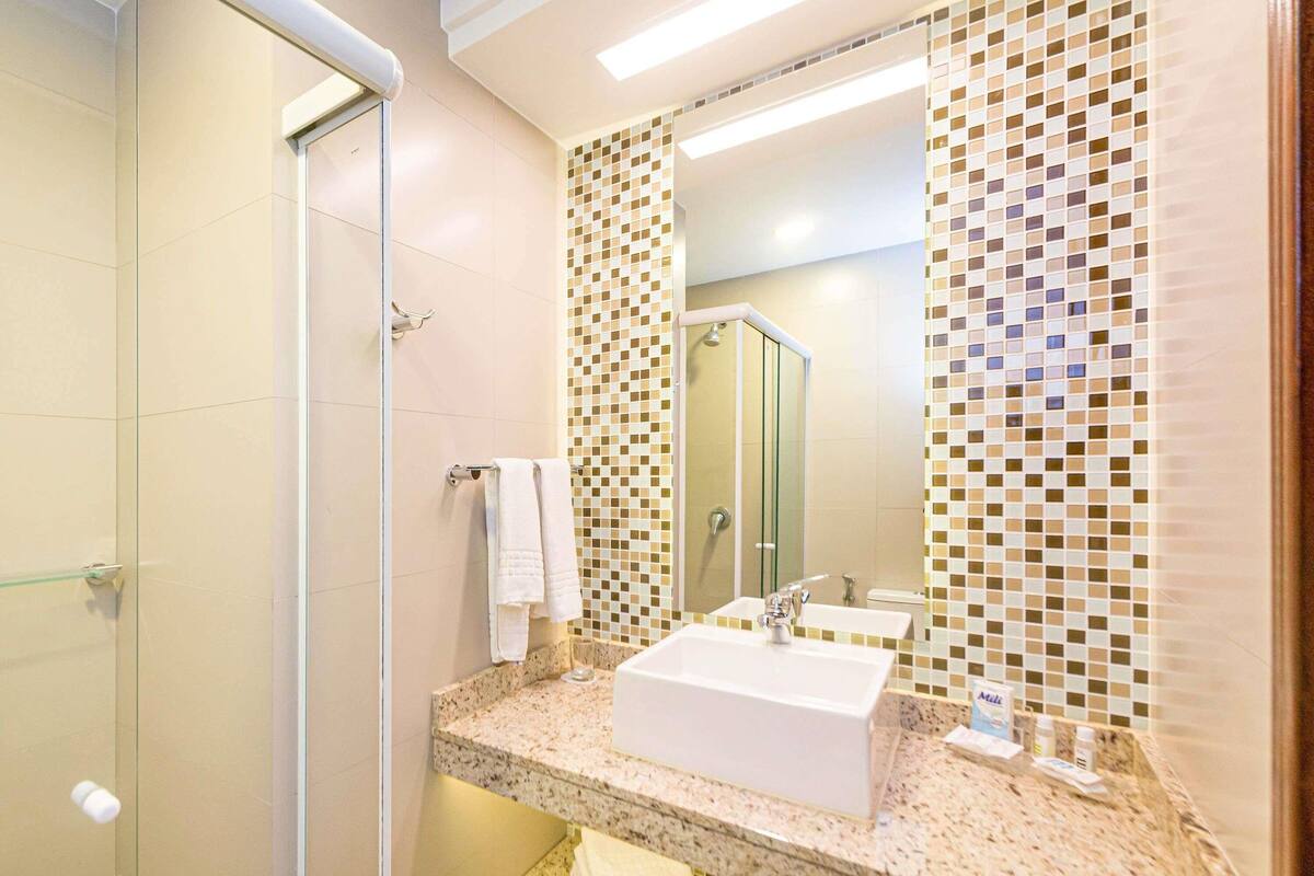 Un baño con ducha, lavabo y espejo.