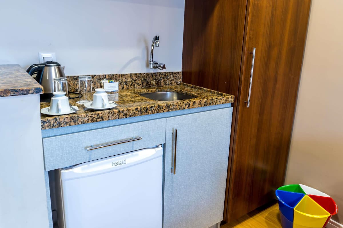A kitchen with granite countertops, a stainless steel sink, a coffee maker, a kettle, and a dishwasher.