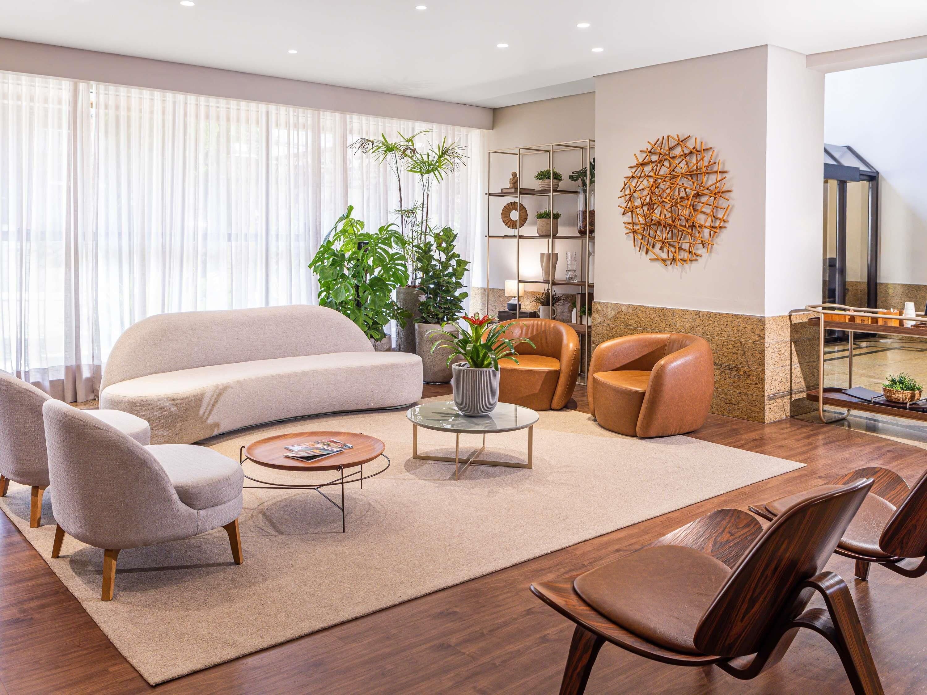Una sala de estar moderna con un sofá, sillones, una mesita de centro y un elemento decorativo en la pared.