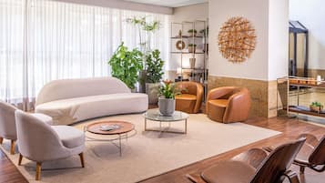 Una sala de estar moderna con un sofá, sillones, una mesita de centro y un elemento decorativo en la pared.