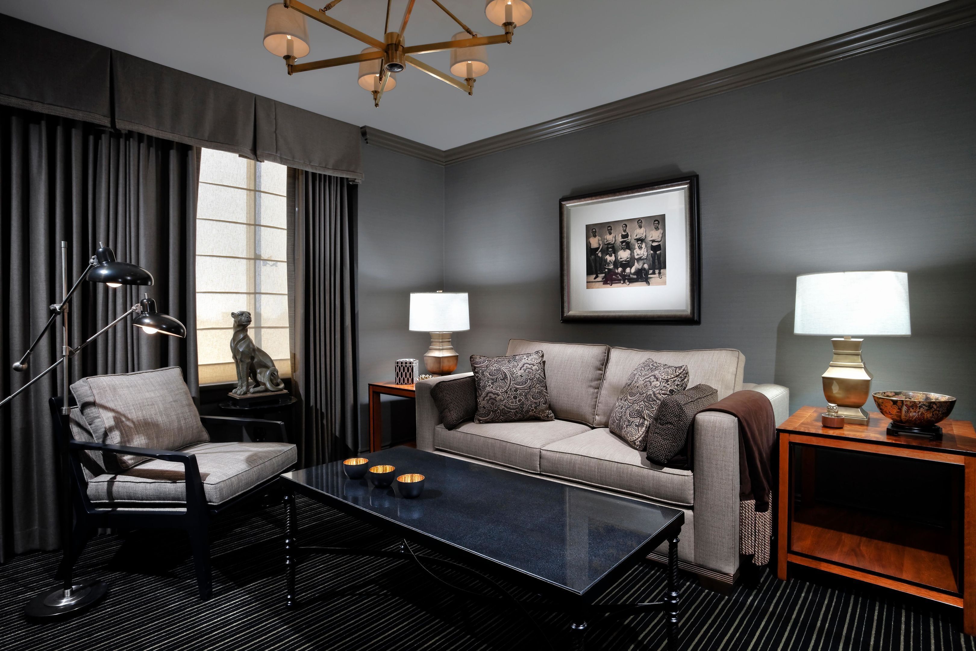 A modern living room with a sofa, armchair, coffee table, and lamps.