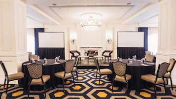 A conference room with a hexagonal patterned carpet, round tables, and chairs with patterned upholstery.