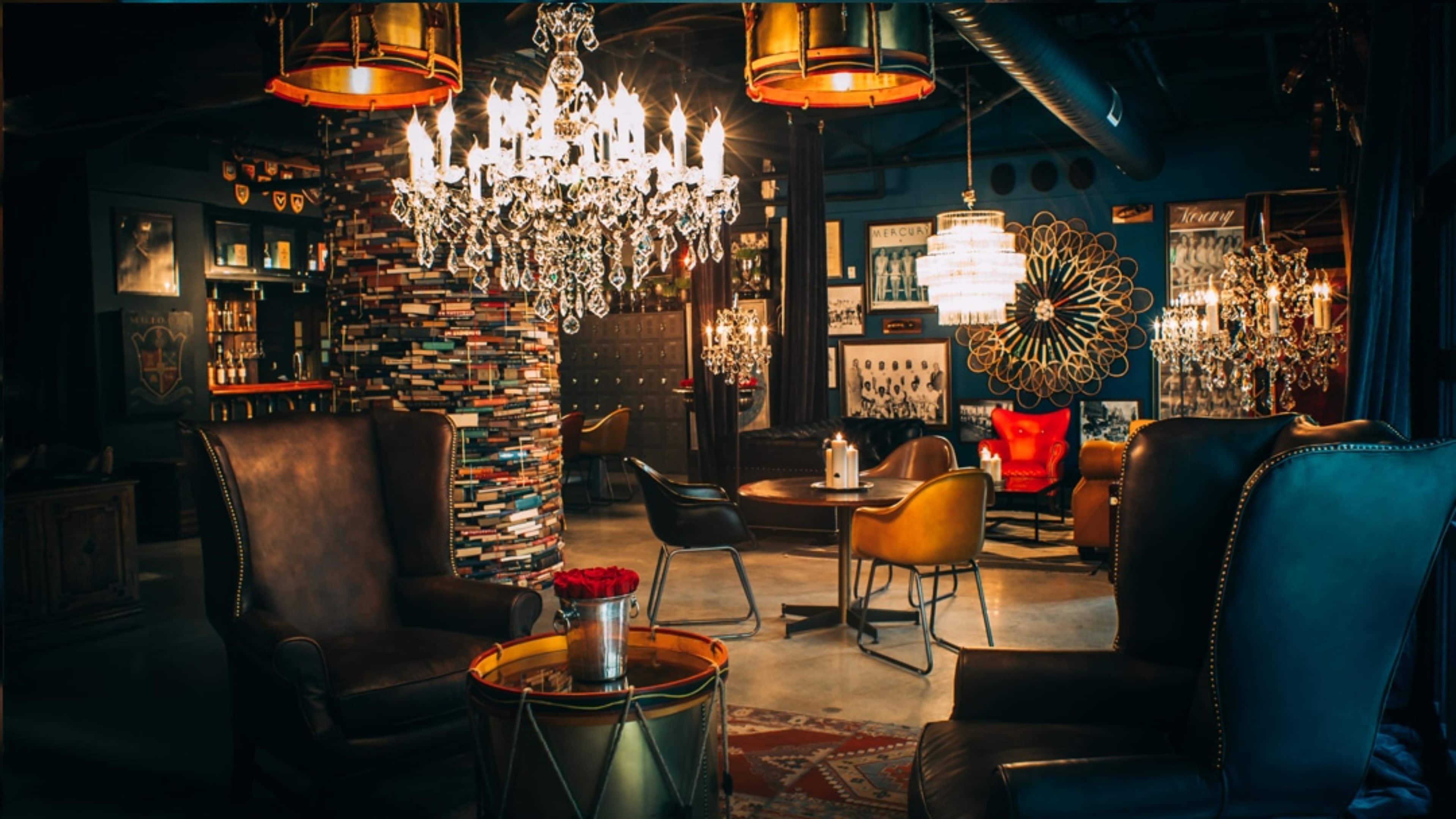 A cozy lounge area with leather sofas, a chandelier, and a wall of books.