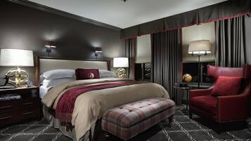 A hotel room with a large bed, a red armchair, a small table, and a globe on a nightstand.