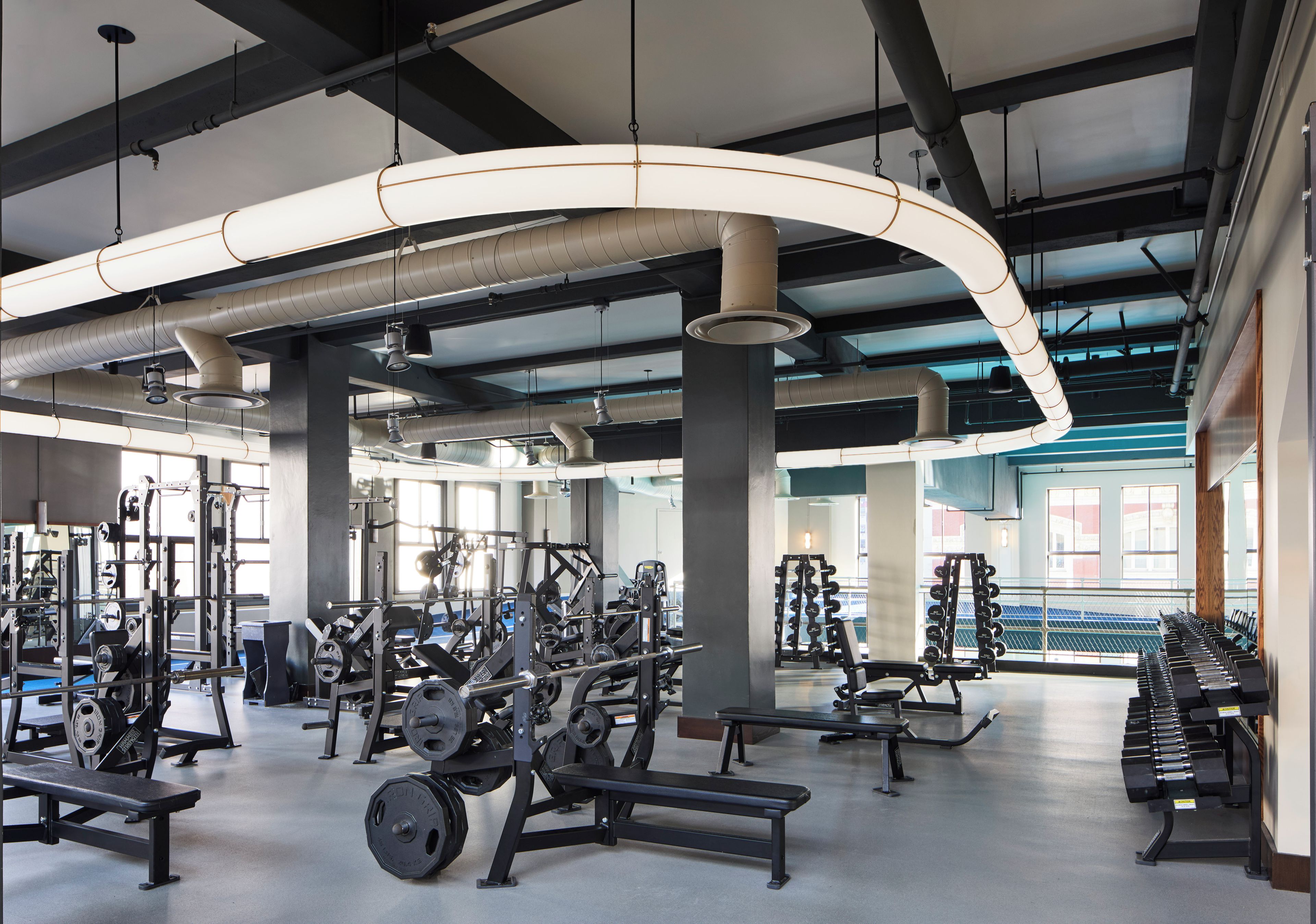 Un gimnasio con diversos equipos de ejercicio, incluyendo bancos de pesas y mancuernas.