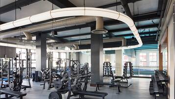 Un gimnasio con diversos equipos de ejercicio, incluyendo bancos de pesas y mancuernas.