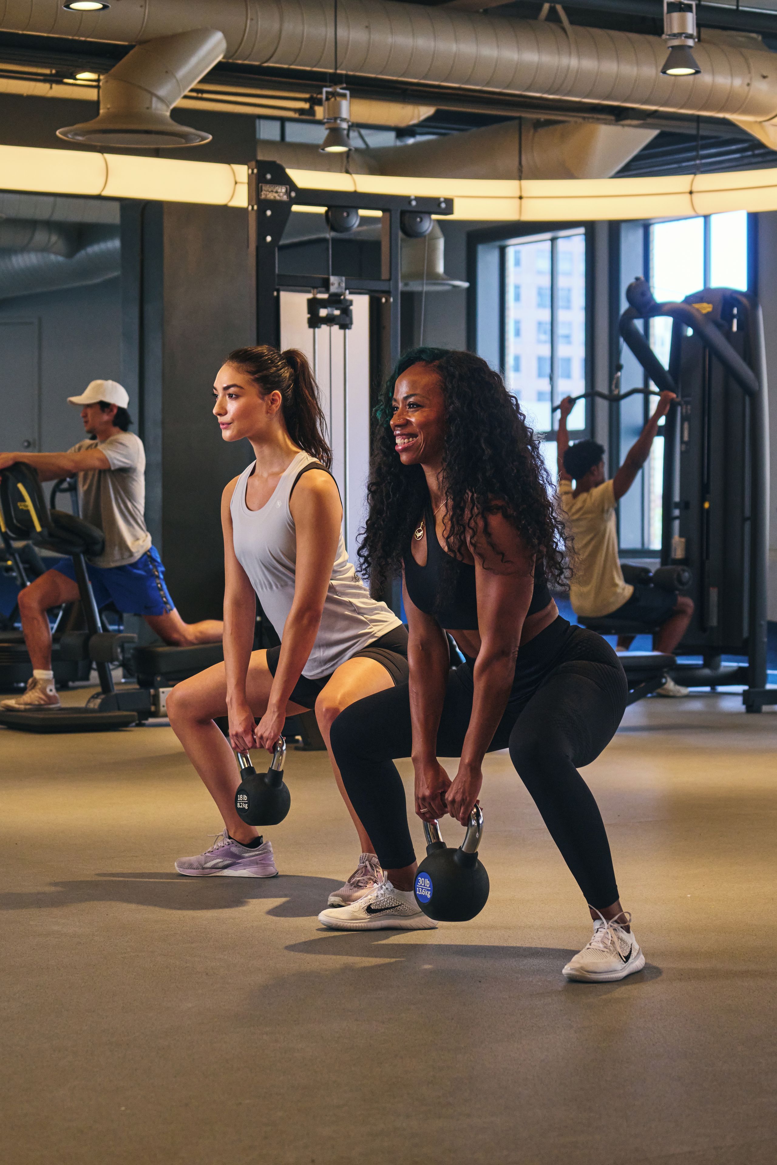 A gym with exercise equipment and people working out.