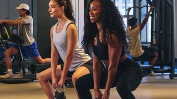 A gym with exercise equipment and people working out.