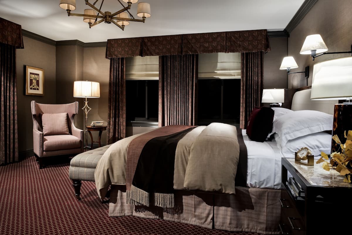 Habitación de hotel con una cama grande, una silla, un escritorio y una lámpara.