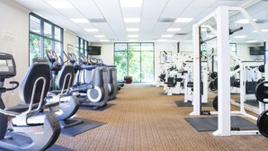Een fitnessruimte met loopbanden, elliptische trainers en gewichten.