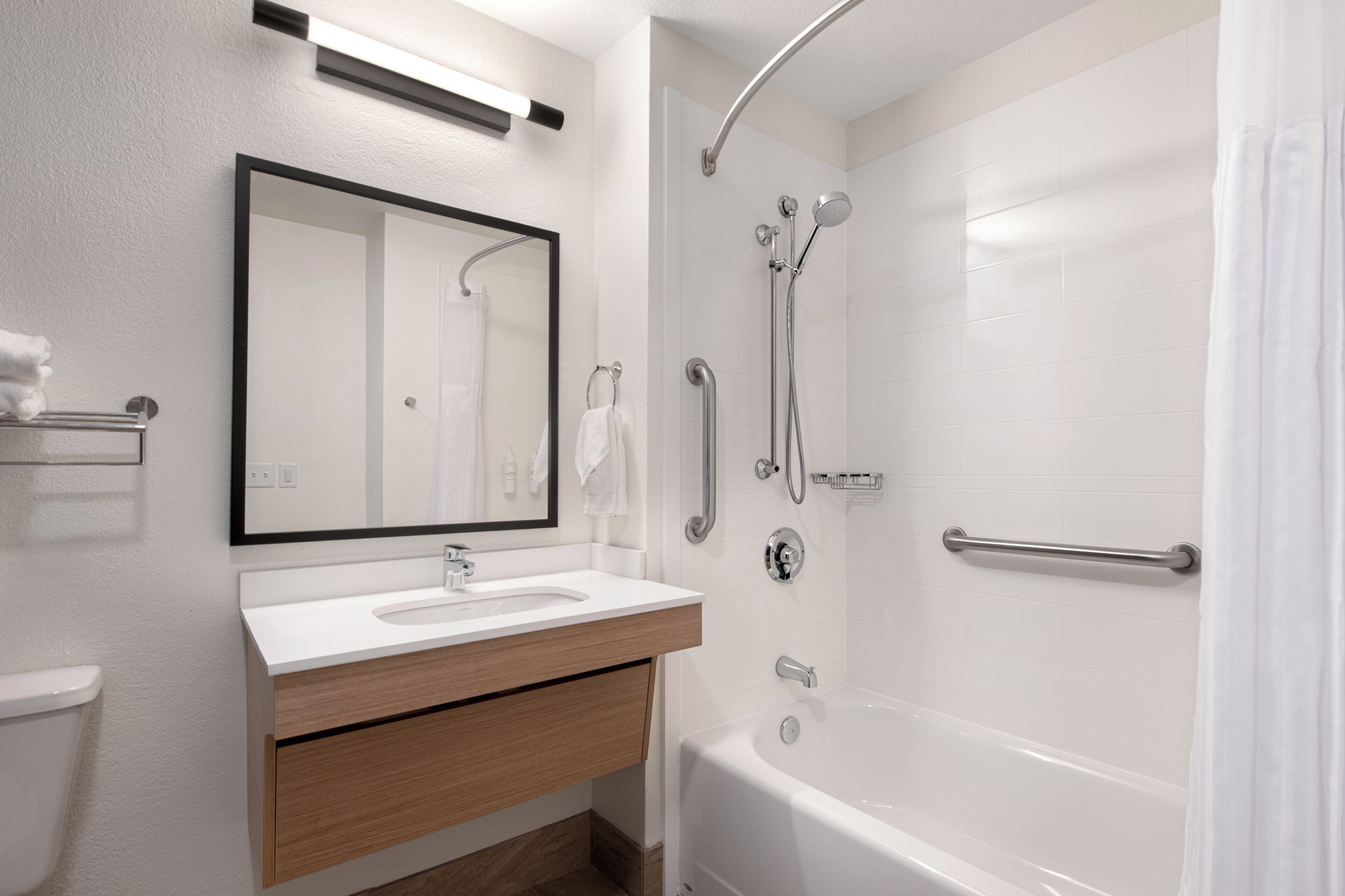 Een moderne badkamer met een wit wastafelmeubel, spiegel en bad.