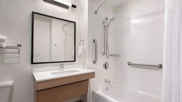 A modern bathroom with a white sink, mirror, and bathtub.