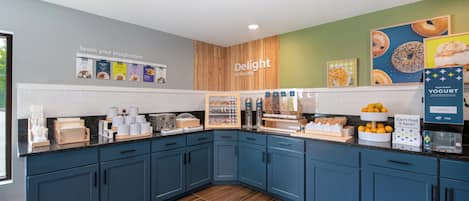 Cocina moderna con armarios azules, un muro decorativo de madera y diversos alimentos exhibidos.