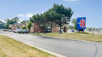 A Motel 6 sign, a brick building, and parked cars on a street.