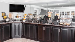 A modern kitchen with dark cabinetry, a flat-screen TV, and various appliances like a coffee maker and waffle maker. - Baymont by Wyndham Glenview (Glenview)