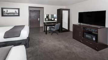 Habitación de hotel con cama, escritorio, silla, televisor y microondas.