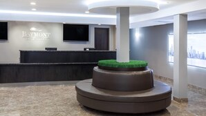 A Baymont Inn & Suites reception area with a modern design, a reception desk, and a circular seating area with a green accent. - Baymont by Wyndham Glenview (Glenview)