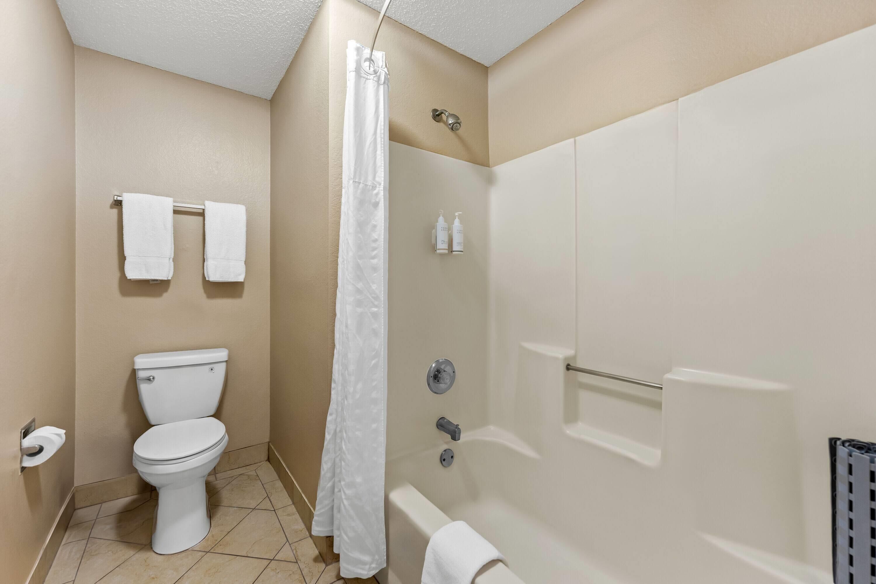 A bathroom with a toilet, shower, and bathtub.