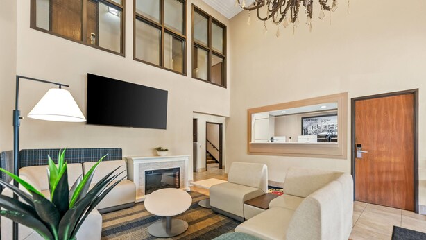 Una sala de estar moderna con televisor de pantalla plana, chimenea y escalera que sube a un nivel superior.