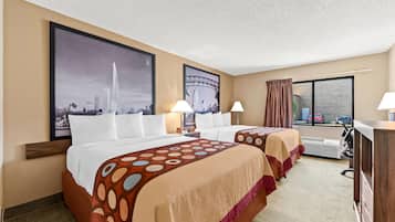 Habitación de hotel con dos camas, un ventanal amplio, un escritorio y vistas a la ciudad.