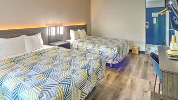 A hotel room with two beds, a desk, and a bathroom.