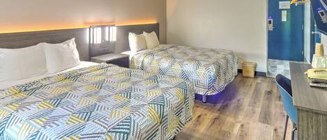 A hotel room with two beds, a desk, and a bathroom.
