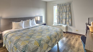 A hotel room with a bed, a nightstand, a window with curtains, a radiator, and a desk with a chair. - Motel 6 Libertyville, IL (Libertyville)