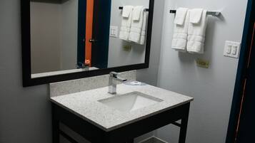 A bathroom with a white sink, a mirror, and two towels hanging on the wall.