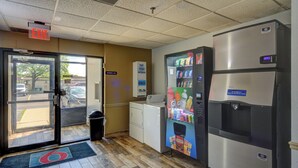 A commercial kitchen with a vending machine, a refrigerator, and a trash can. - Motel 6 Libertyville, IL (Libertyville)