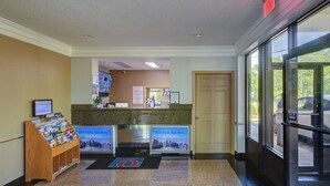 A reception area with a desk, a computer monitor, a bulletin board, and a display stand with brochures. - Motel 6 Libertyville, IL (Libertyville)