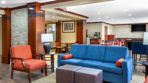 A hotel lobby with a blue sofa, orange armchair, and a stone accent wall. - Comfort Inn Hoffman Estates - Schaumburg (Hoffman Estates)