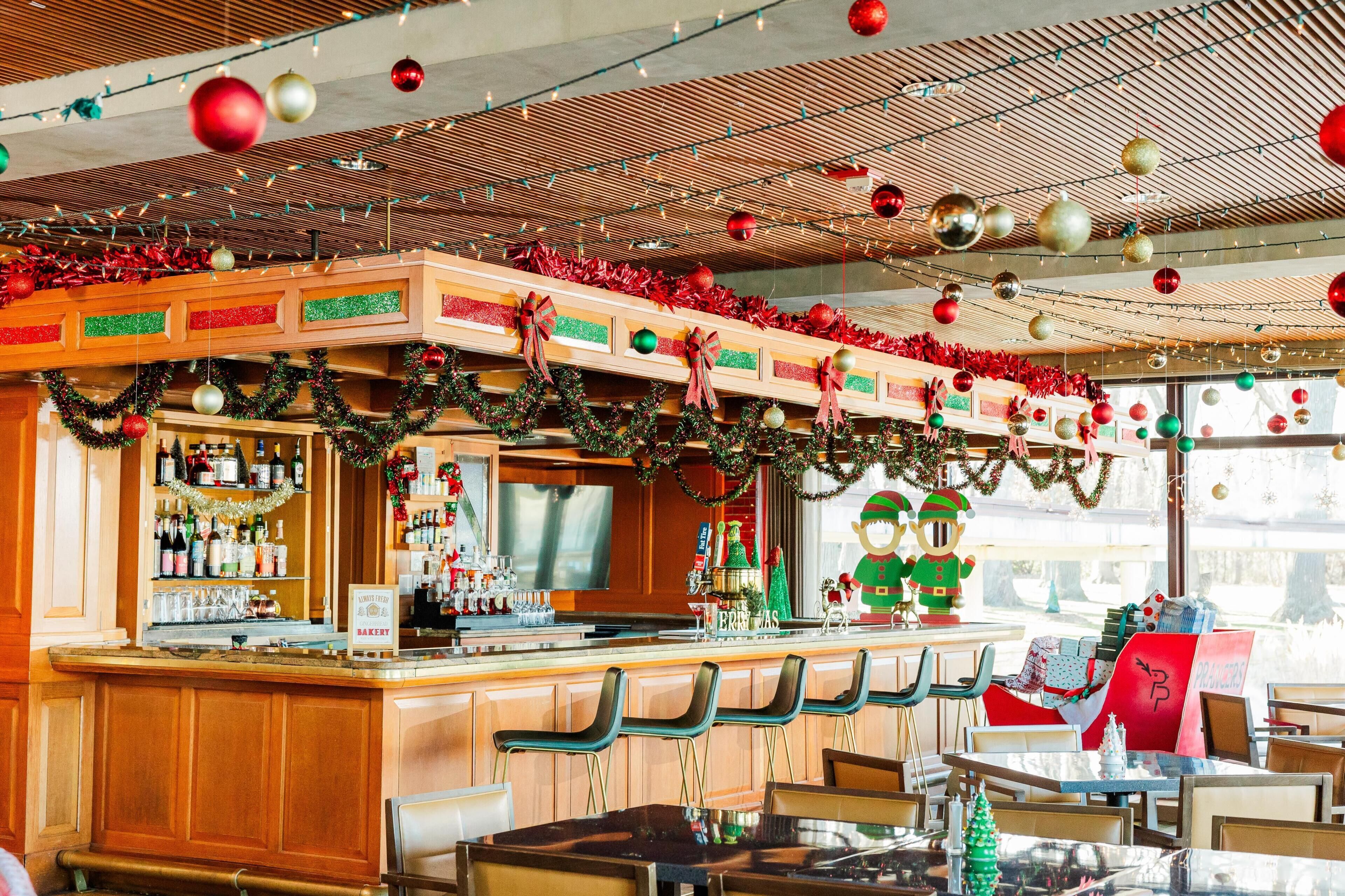 Un espace bar avec des comptoirs en bois, des tabourets de bar et une décoration festive.