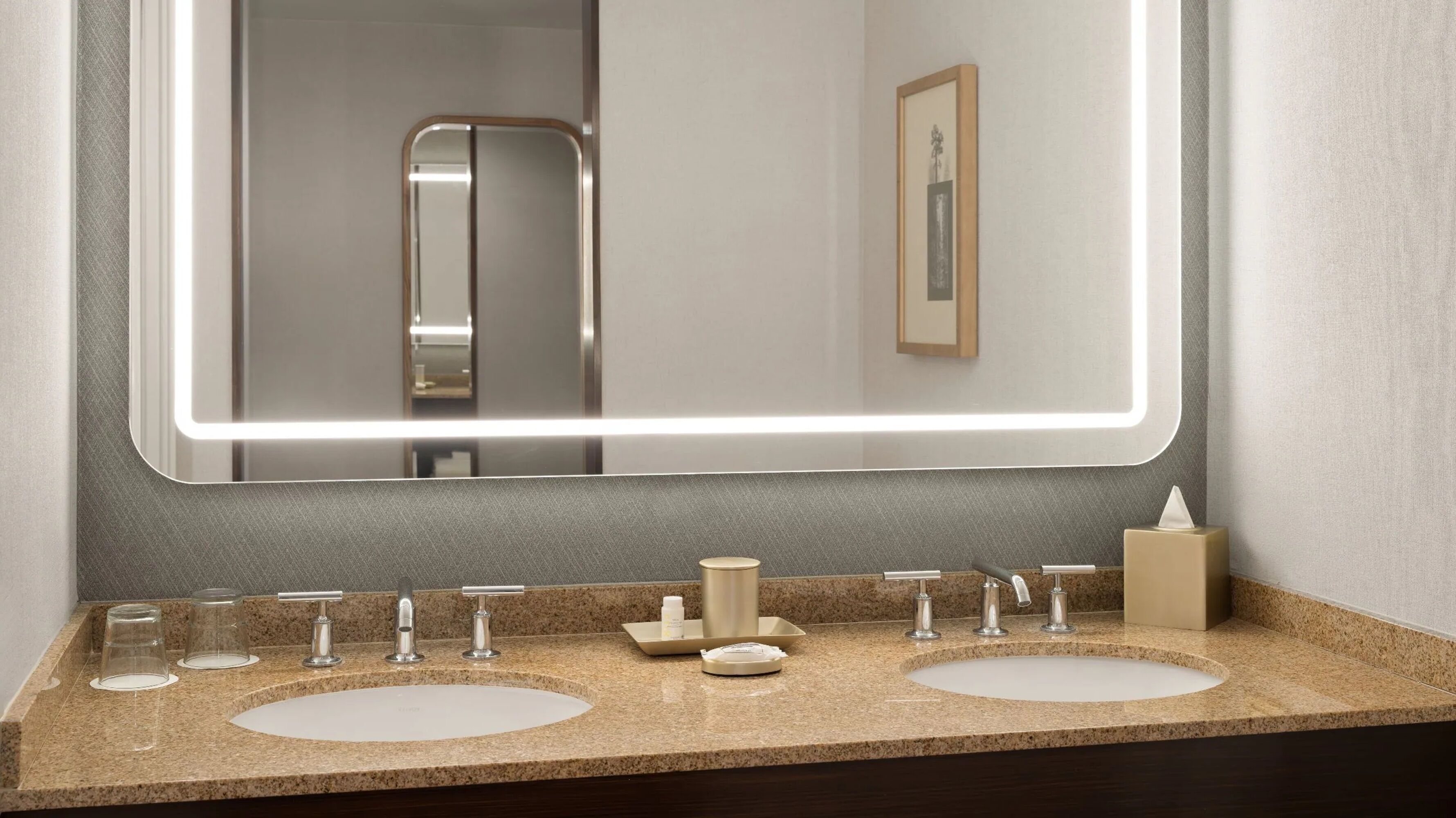 A bathroom with two sinks, a mirror, and a framed picture on the wall.