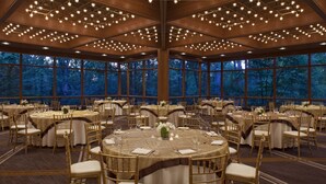 Un salón de banquetes con mesas redondas, sillas y candelabros.