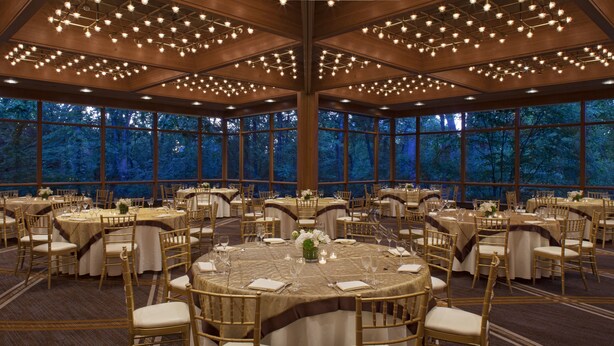 Un salón de banquetes con mesas redondas, sillas y candelabros.