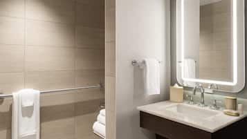 A modern bathroom with a shower, a sink with a mirror, and a towel rack.