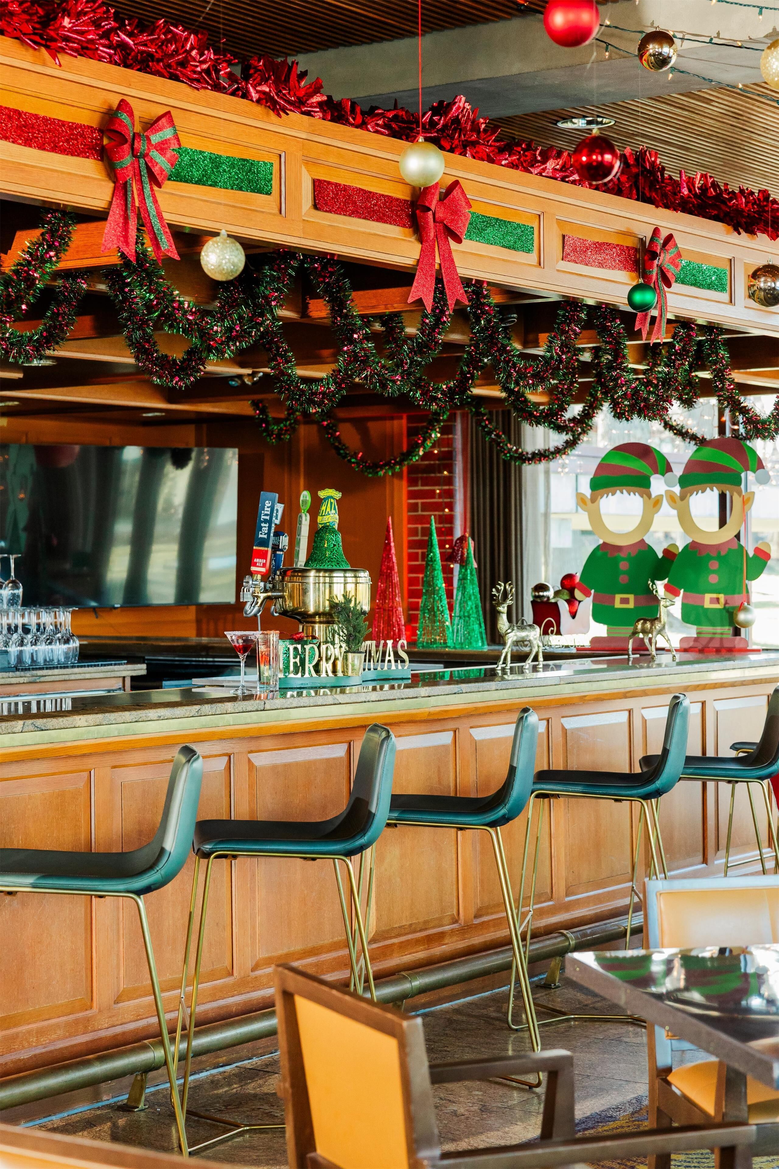 A bar area with festive decorations, a Christmas tree, and a 'Merry Christmas' sign.