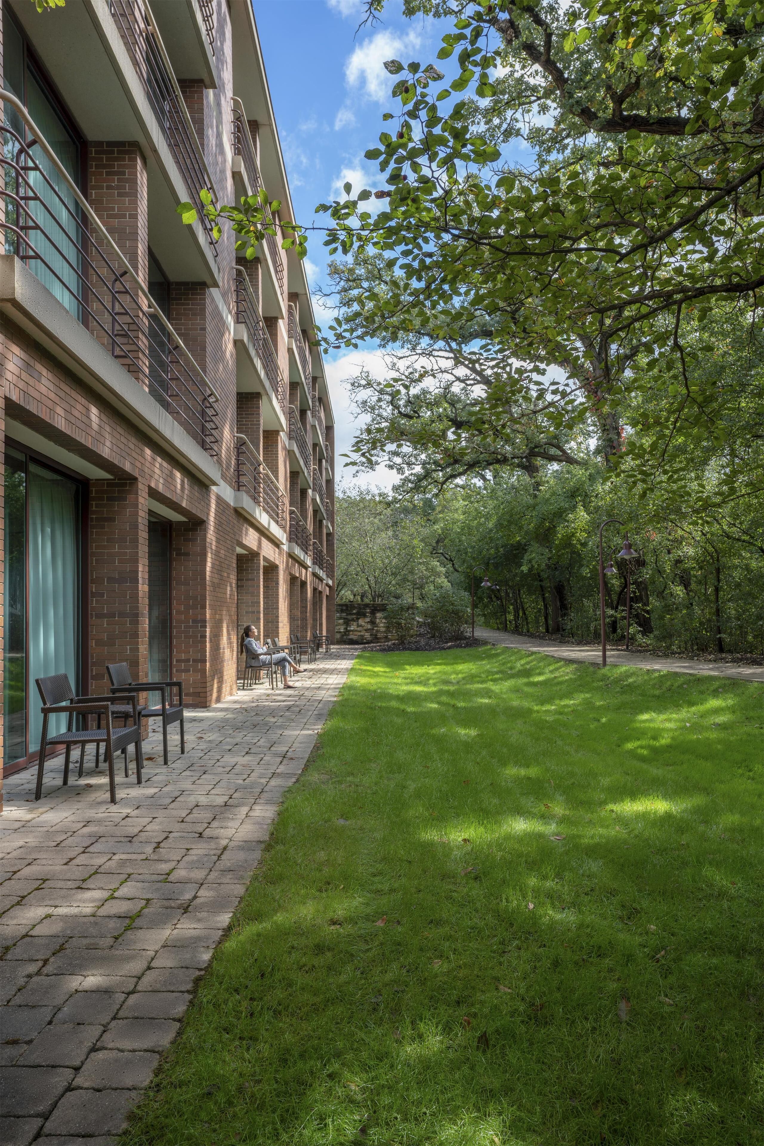 A building with a brick facade, outdoor seating, and a well-maintained lawn.