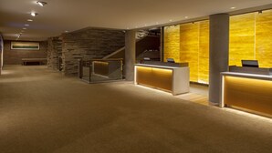 Un área de recepción con pared de piedra, un banco de madera y un mostrador de recepción con separador de vidrio.