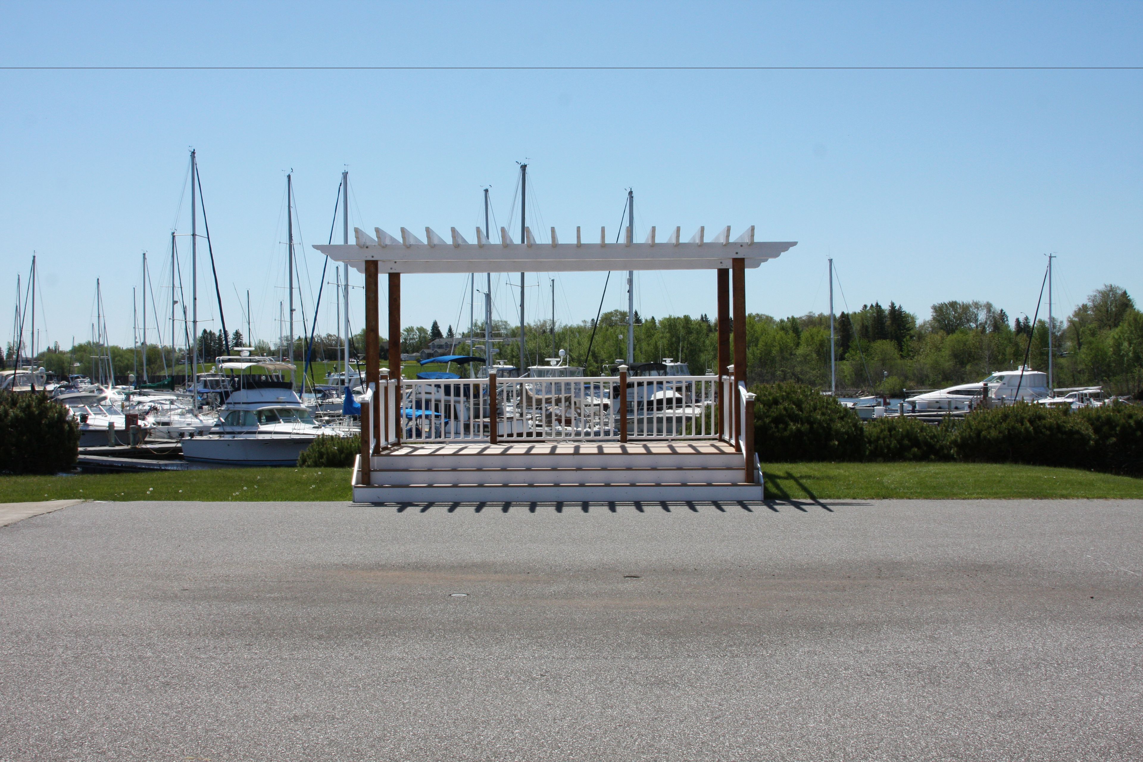A covered outdoor seating area with a railing, surrounded by a marina with various boats.