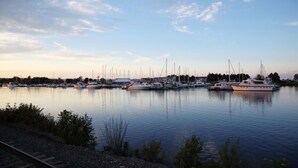 A marina with multiple boats docked, calm water, and a clear sky.