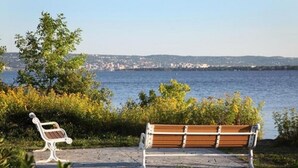 A bench by a waterfront with a view of a cityscape in the distance.