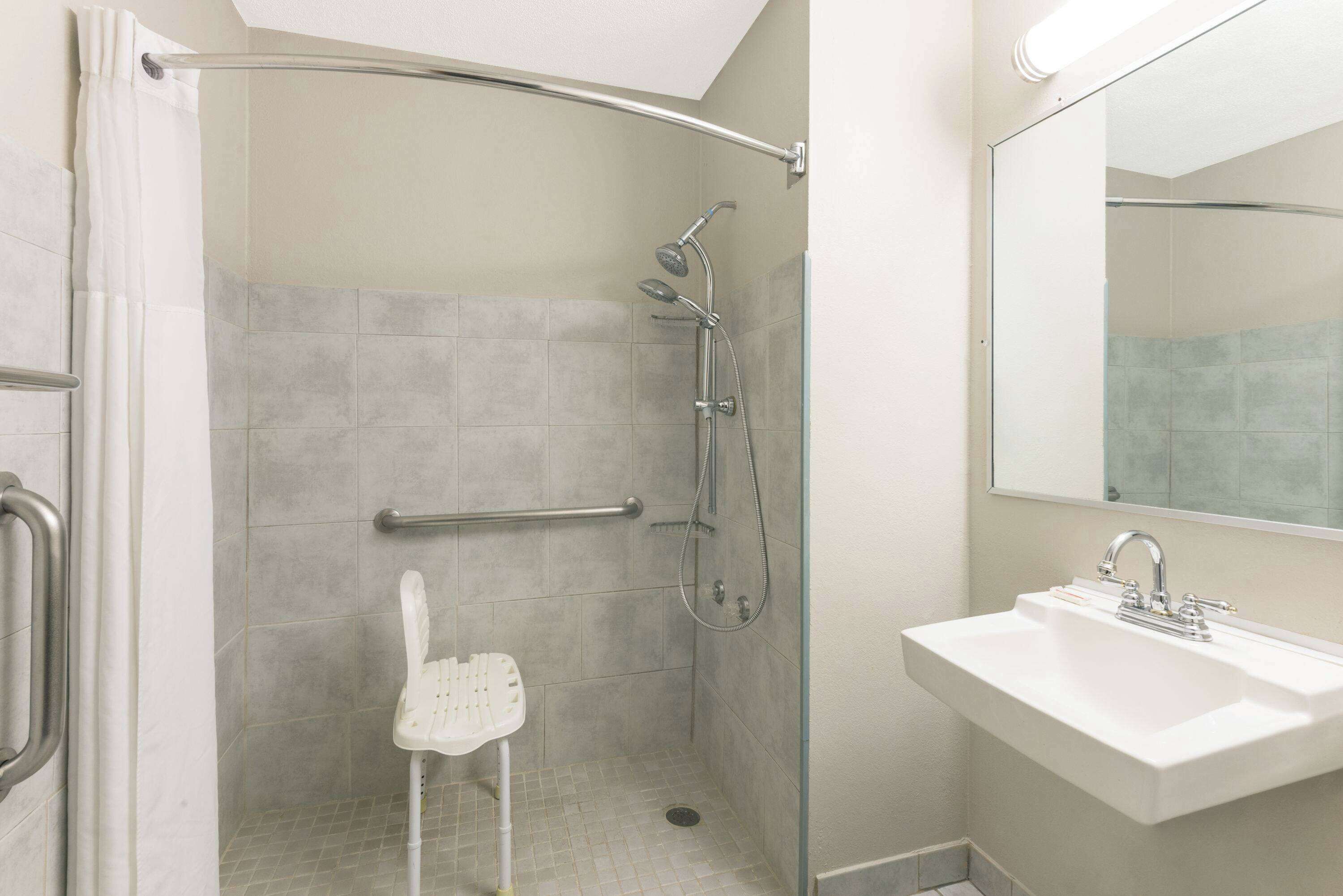 A bathroom with a shower, a sink, and a mirror.