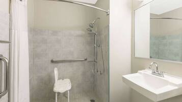 A bathroom with a shower, a sink, and a mirror.