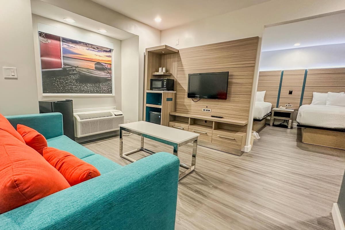 A modern hotel room with a sofa, a TV, a small table, and a bed.