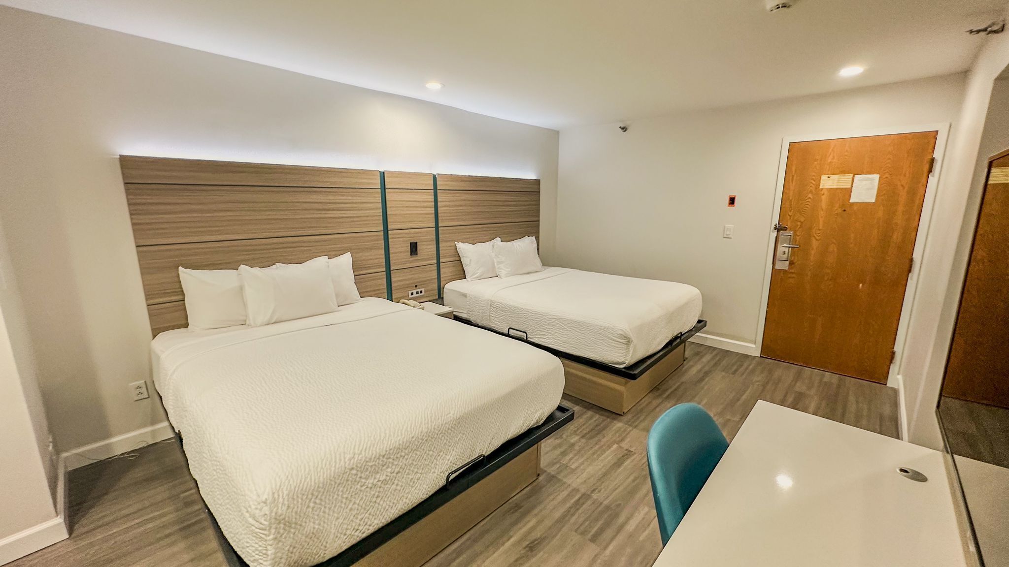 A hotel room with two beds, a desk, and a chair.
