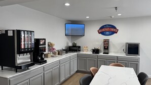 A breakfast area with a coffee machine, microwave, toaster, and a TV mounted on the wall. - Baymont by Wyndham Henrietta/Rochester (Henrietta)