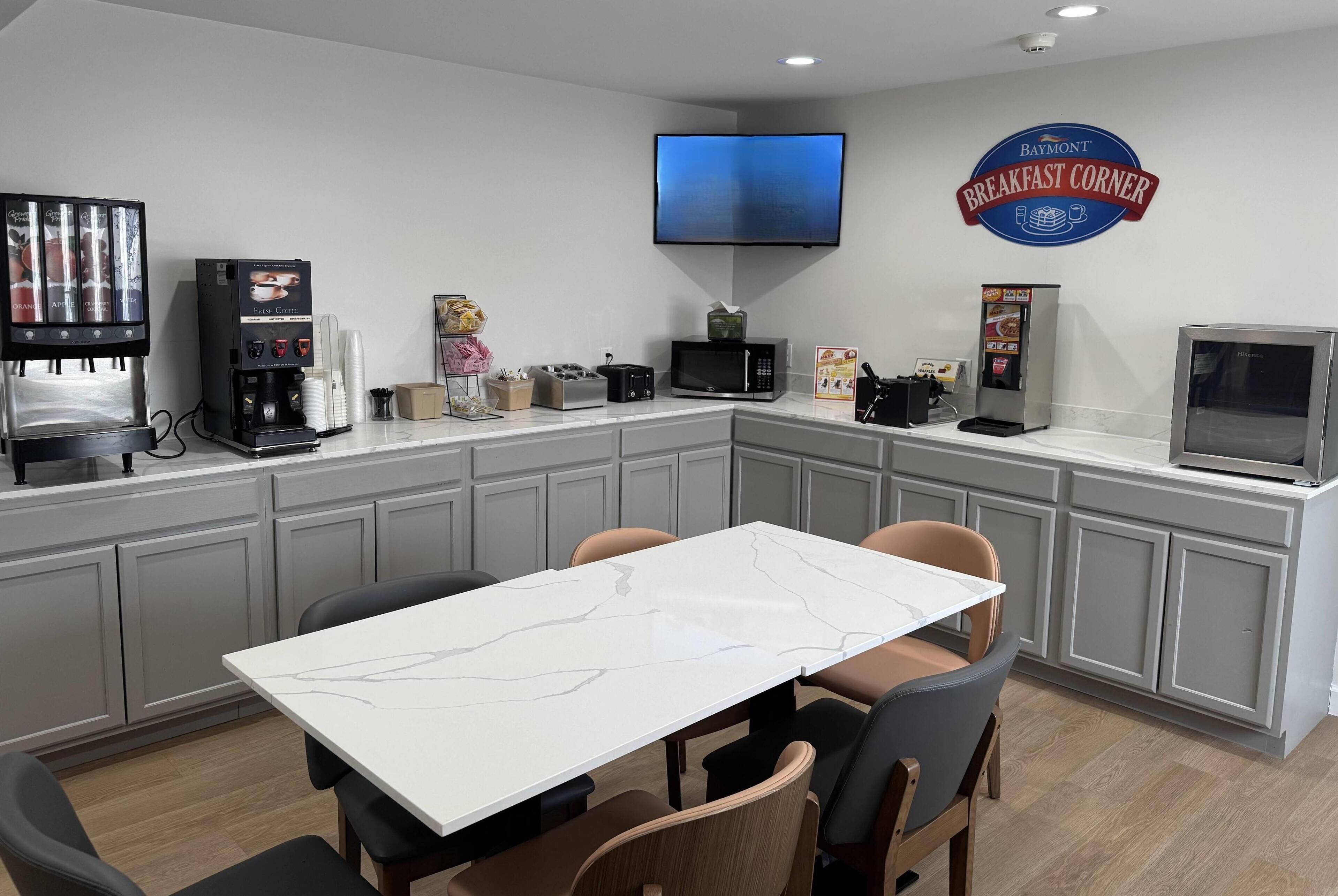 A modern kitchen with a coffee machine, microwave, toaster, and a flat-screen TV.